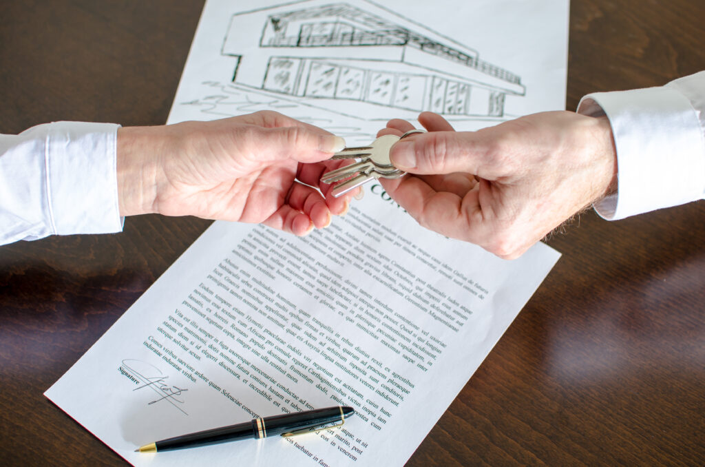 Estate agent giving house keys to customer after contract signature
